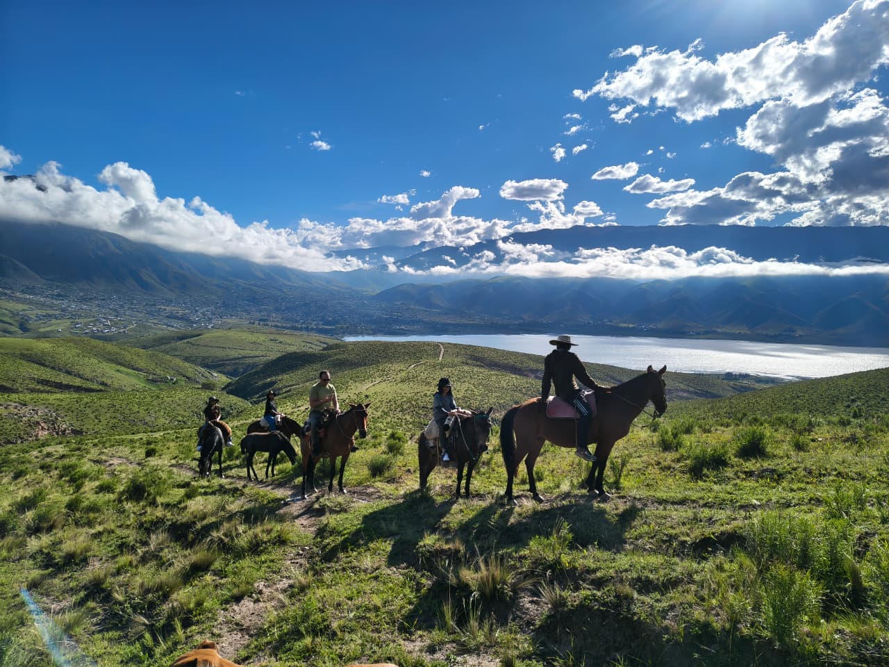 Grupo a caballo sobre los cerros verdes con vista panorámica al Dique La Angostura, El Mollar, Tafí del Valle